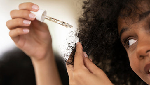 Woman applying hair serum to her curly hair, questioning if spironolactone can cause hair loss